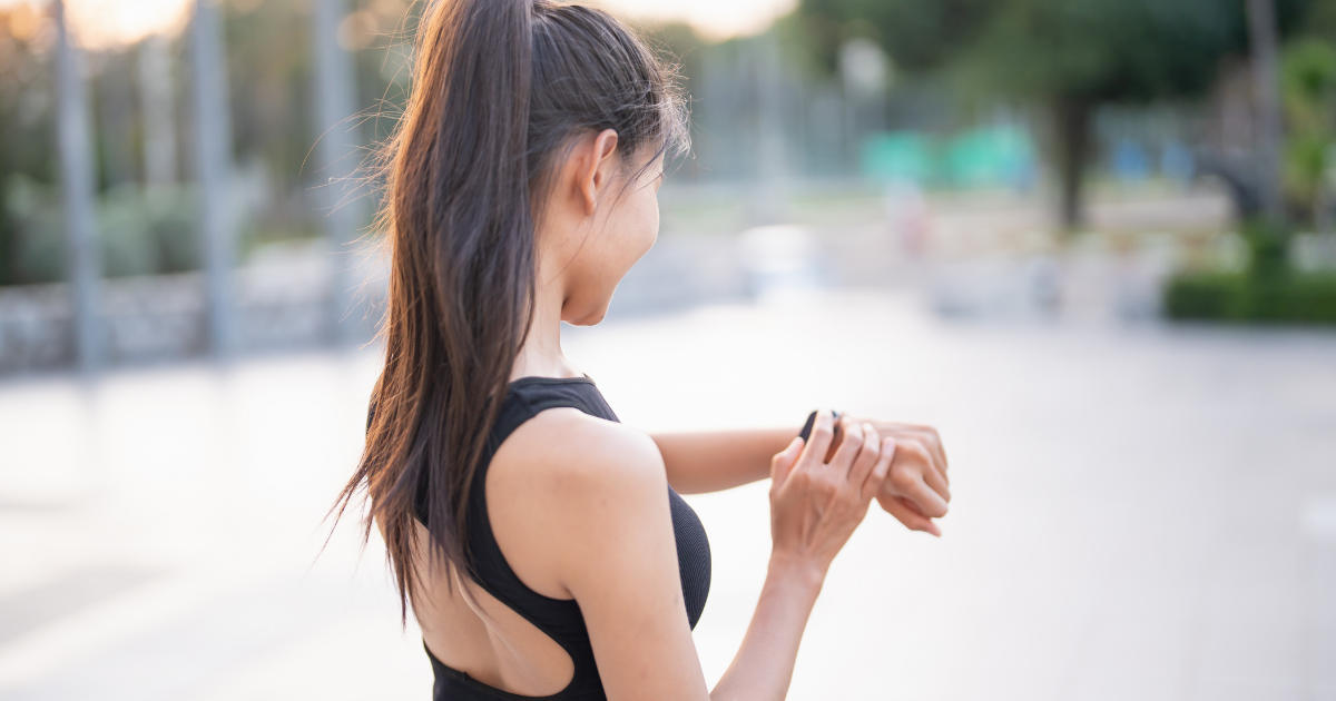 Woman in sportswear outdoors checking her resting heart rate on a fitness-tracker watch
