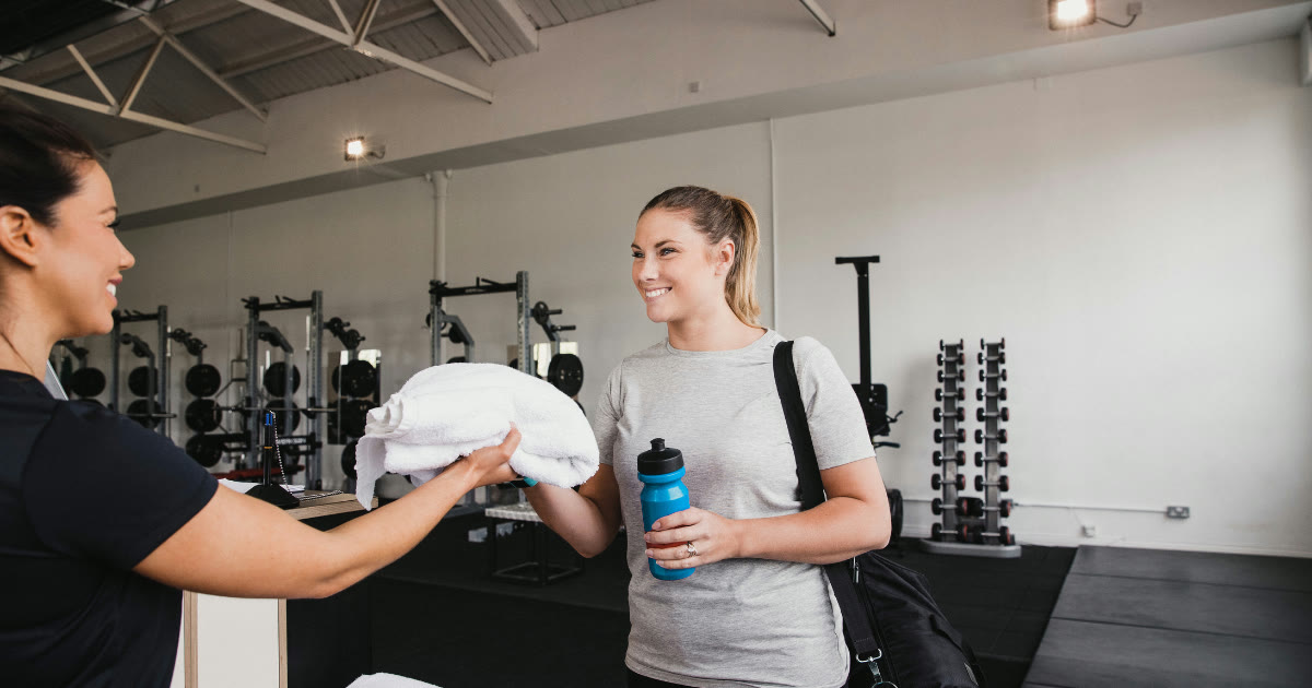 New client arriving for her first personal training session, being handed a towel by her trainer at a Sydney gym